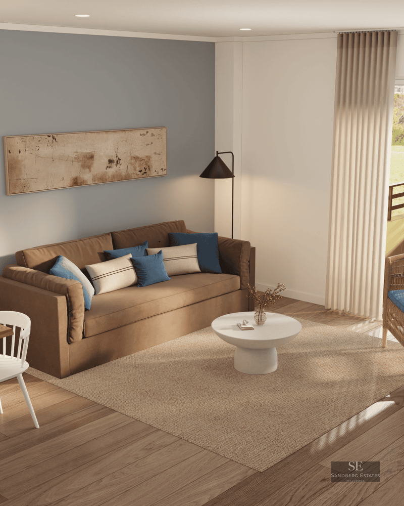 Salon avec canapé marron, fauteuil en osier, tapis en jute et porte vitrée ouvrant sur un balcon ensoleillé.