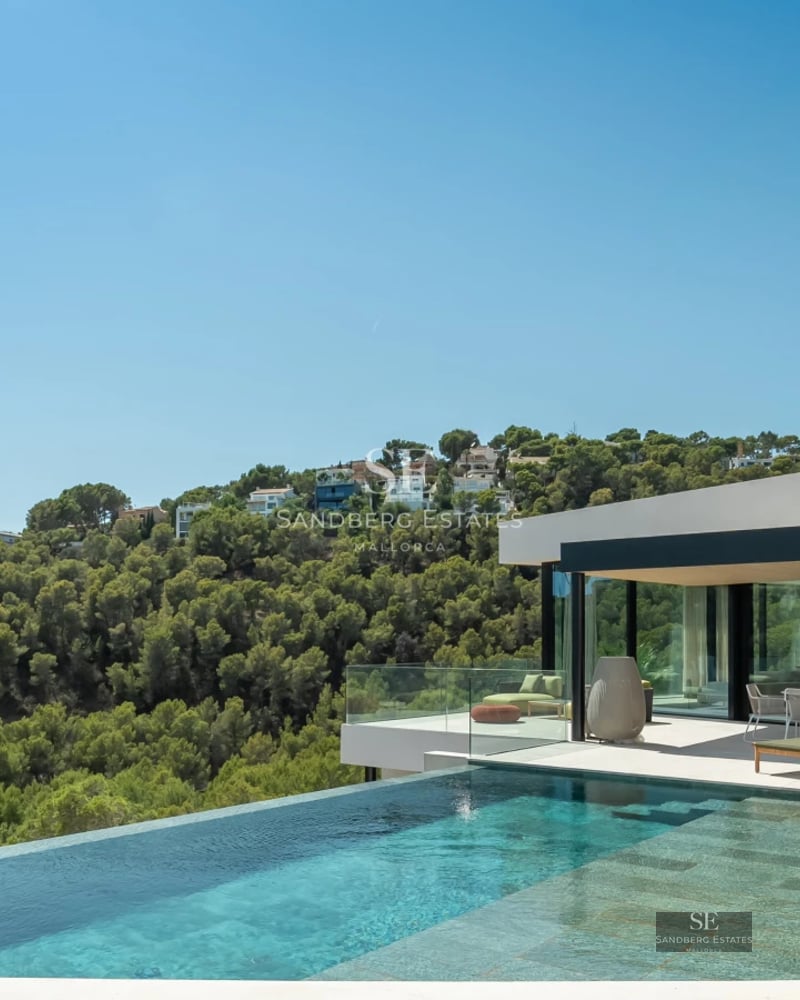 View of a modern villa with infinity pool, terrace, and large windows. Minimalist design with high-quality finishes.