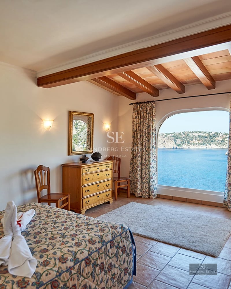 Spacious living room with picture windows, light wood floors, and modern design. Gray sofa and pool view.