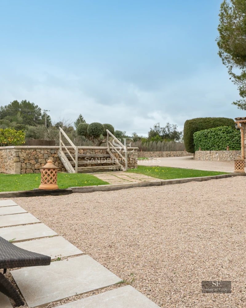 Exterior view of a modern villa featuring a pool, garden, and expansive glass windows reflecting the blue sky.