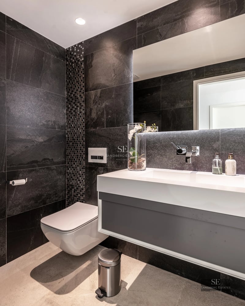 Spacious living room with large windows, leather sofas, modern rug and panoramic views. Warm and elegant lighting.