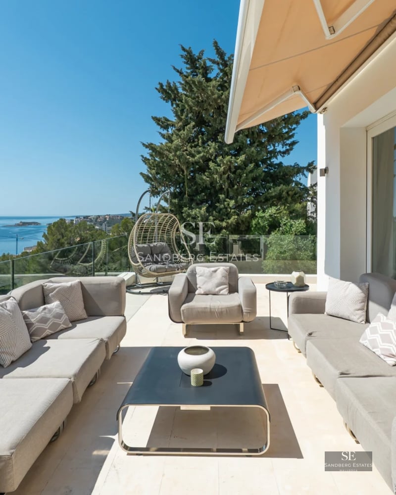 View of a modern swimming pool with sun loungers, surrounded by greenery and with a contemporary house in the background. Minimalist architectural design.