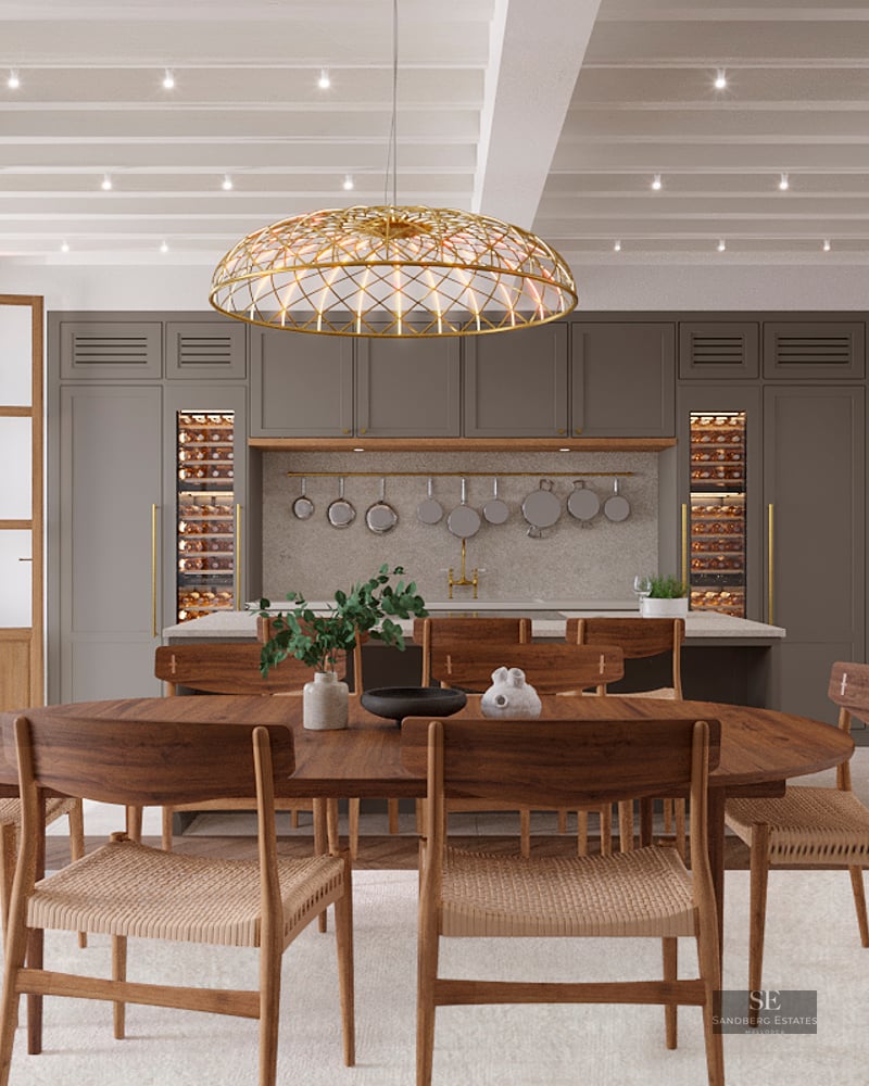 Elegant dining room with a wooden table, woven chairs, a large gold pendant light, and a modern kitchen with wine fridges.