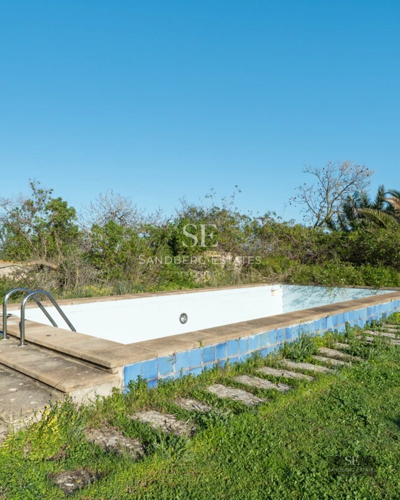 View of a luxury villa with an infinity pool, lush garden, and modern architecture. High-quality finishes and impeccable design.
