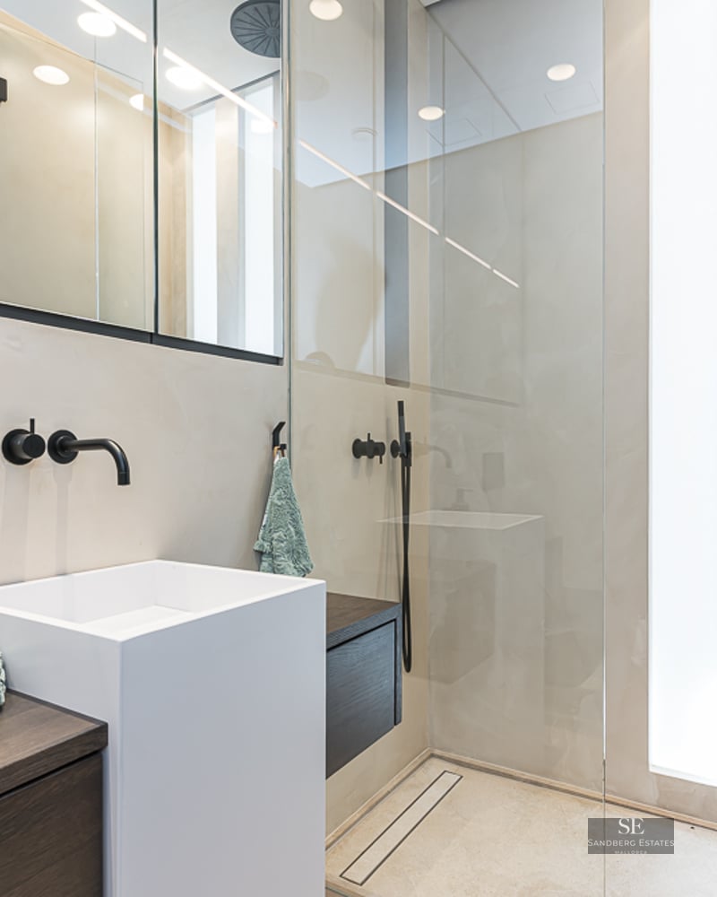 Modern bathroom featuring a white square vessel sink, black wall-mounted faucet, and a glass-enclosed shower.