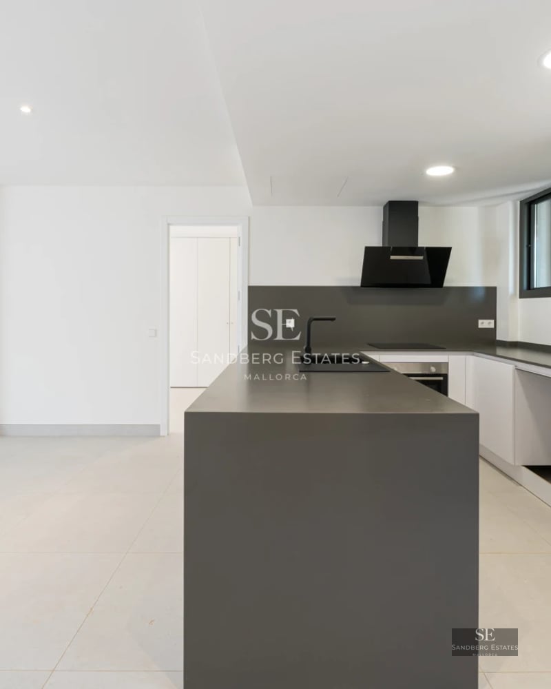 Spacious living room with large windows, light wood flooring, and stunning sea views. Modern furniture and abundant natural light.