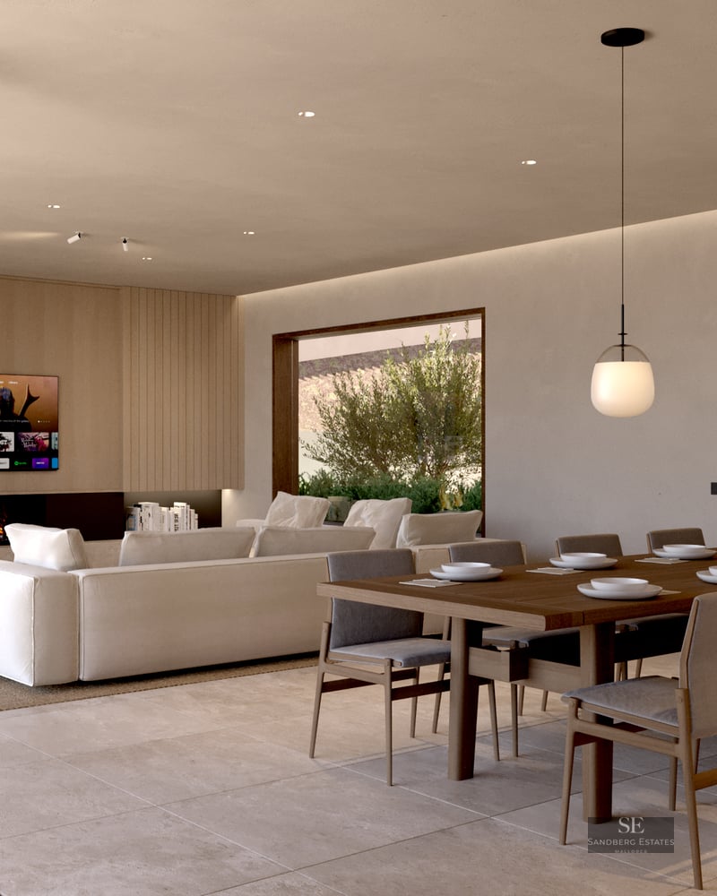 Modern open-plan room with large dining table, white sectional sofa, fireplace, and floor-to-ceiling glass doors.