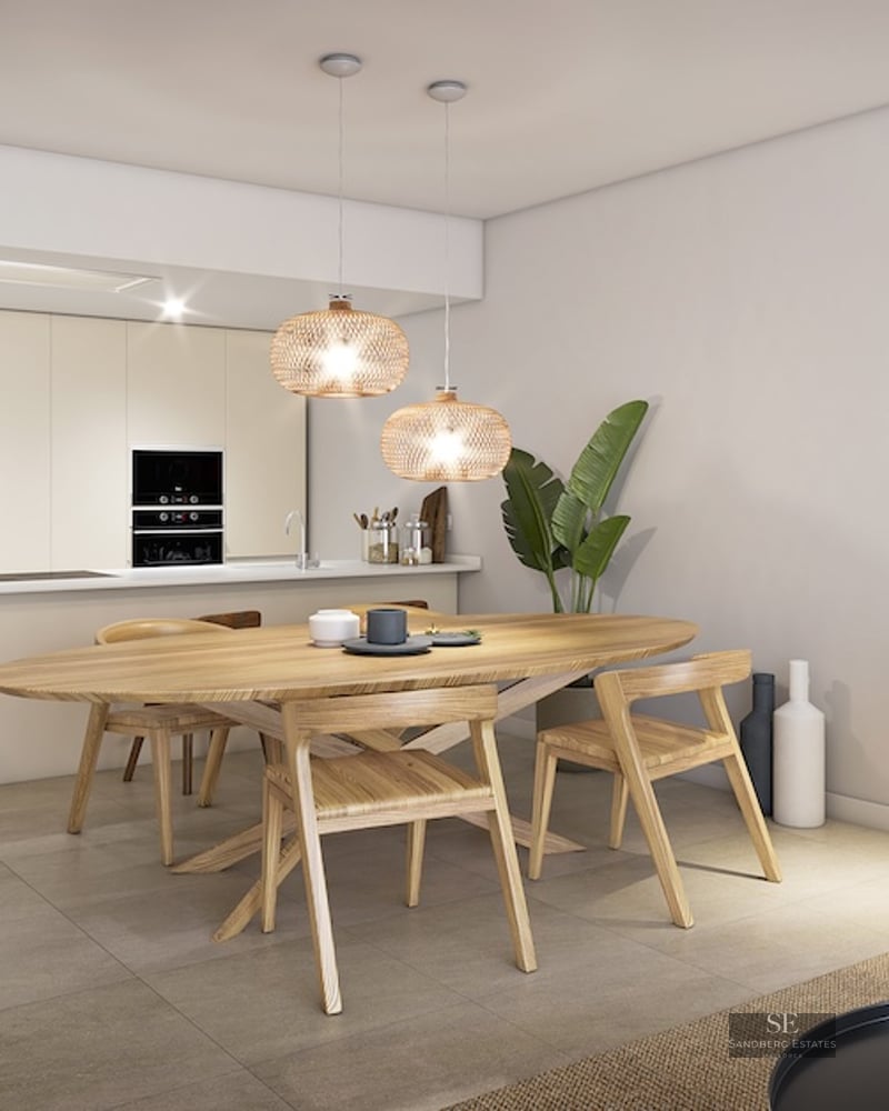 Modern dining area featuring an oval wooden table, wicker pendant lights, and a minimalist integrated kitchen.