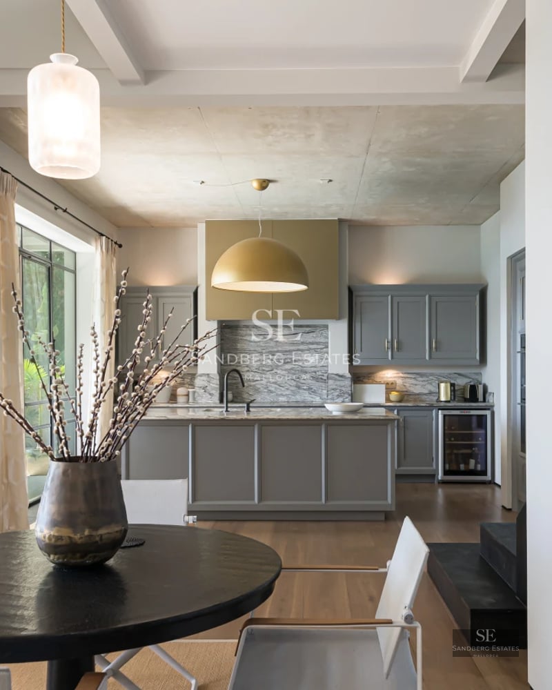 View of a luxurious infinity pool with glass edge, surrounded by a lush garden and modern architecture. Spacious and bright outdoor area.