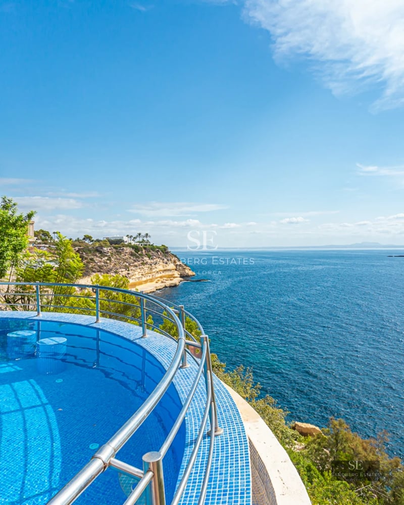 Grand balcon avec vue sur la mer, mobilier moderne, garde-corps en verre. Espace lumineux et élégant. Détails architecturaux design.