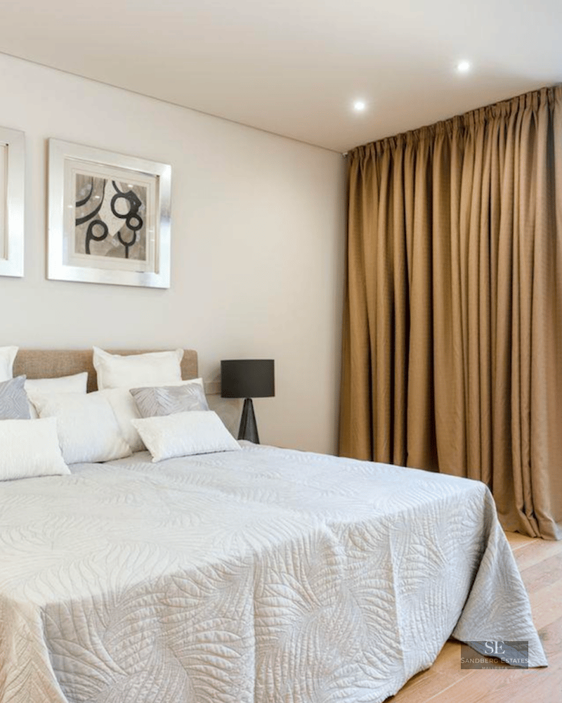 Bright bedroom with a double bed, abstract artwork, and large sliding glass doors leading to a stone patio.