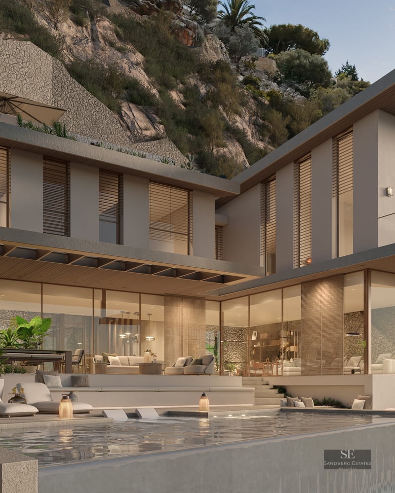 Two-story modern villa with stone walls, floor-to-ceiling glass windows, and an infinity pool at dusk.