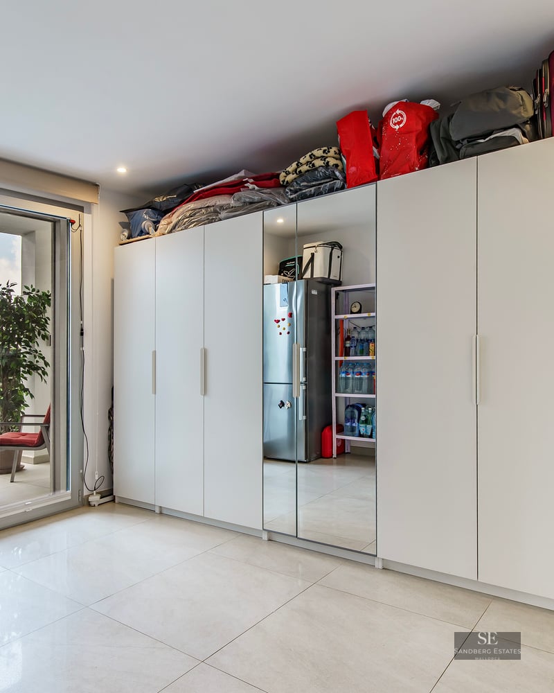 Bright room featuring large white wardrobes and glass doors leading to a furnished outdoor terrace.