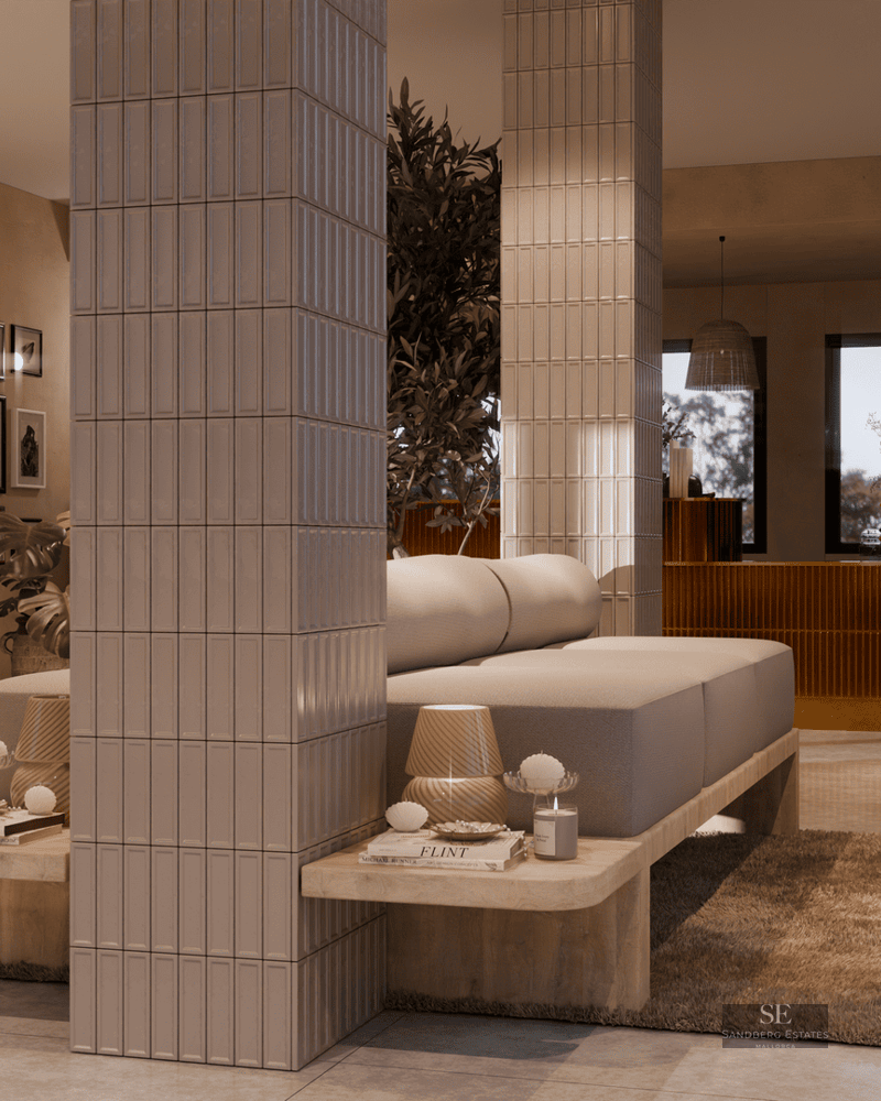 Espace de vie moderne à aire ouverte avec canapés beiges, colonnes carrelées et tons terreux chaleureux.