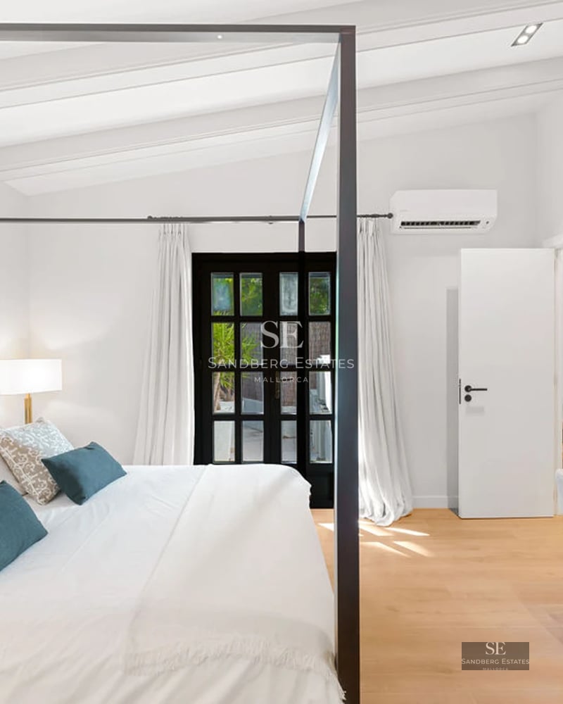 View of a luxurious pool with loungers and umbrellas, surrounded by gardens and a modern house in the background.