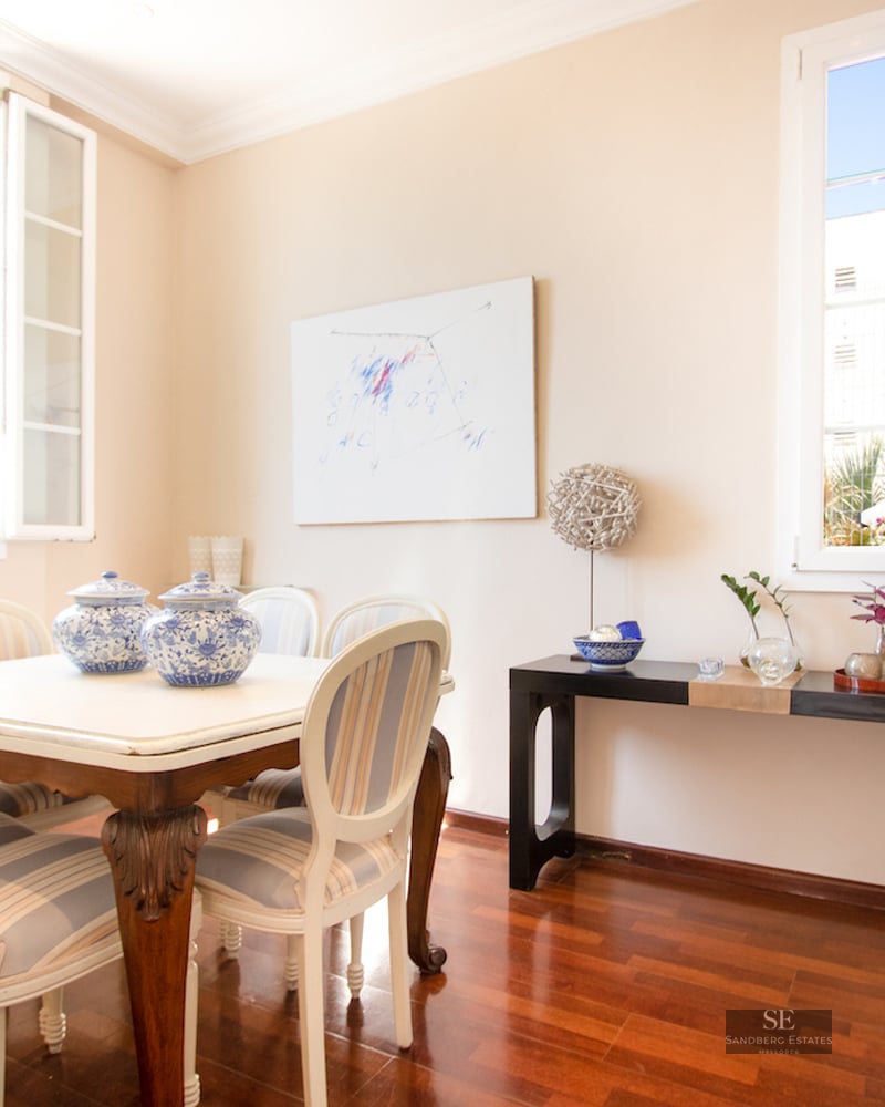 Bright dining room with white table, striped chairs, hardwood floors, and large windows.