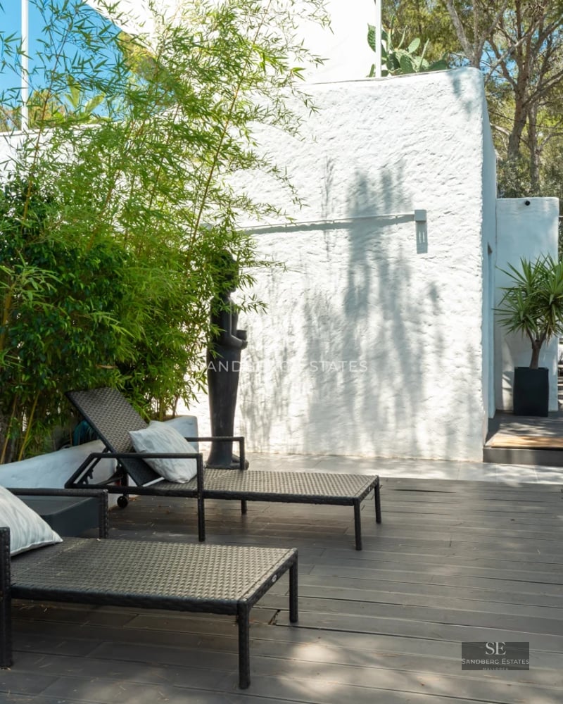 View of modern villa featuring infinity pool, sun loungers, manicured lawn, and minimalist architecture on a sunny day.