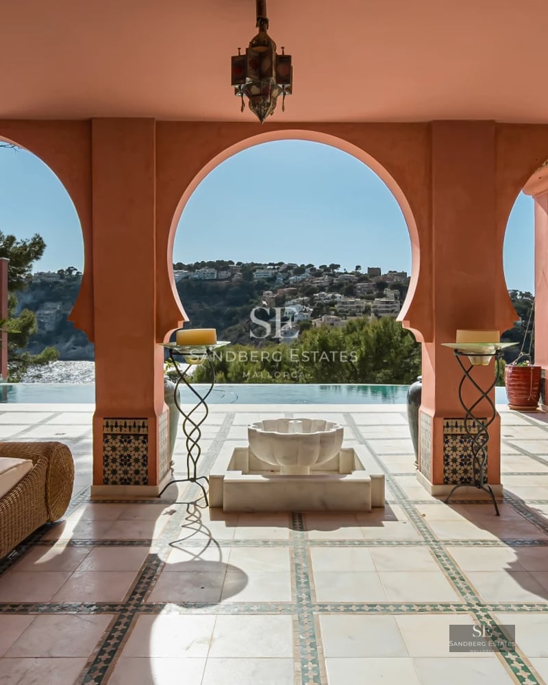 Bright living room featuring a modern fireplace, large windows overlooking the sea, minimalist decor, and designer furniture.