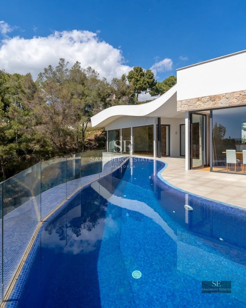 Spacious living room with floor-to-ceiling windows, natural light, minimalist furniture, and access to a terrace with sea views. Modern and elegant design.