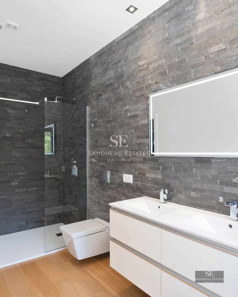 Image of a luxurious pool with sun loungers and umbrellas, surrounded by a modern house with large windows and lush vegetation.