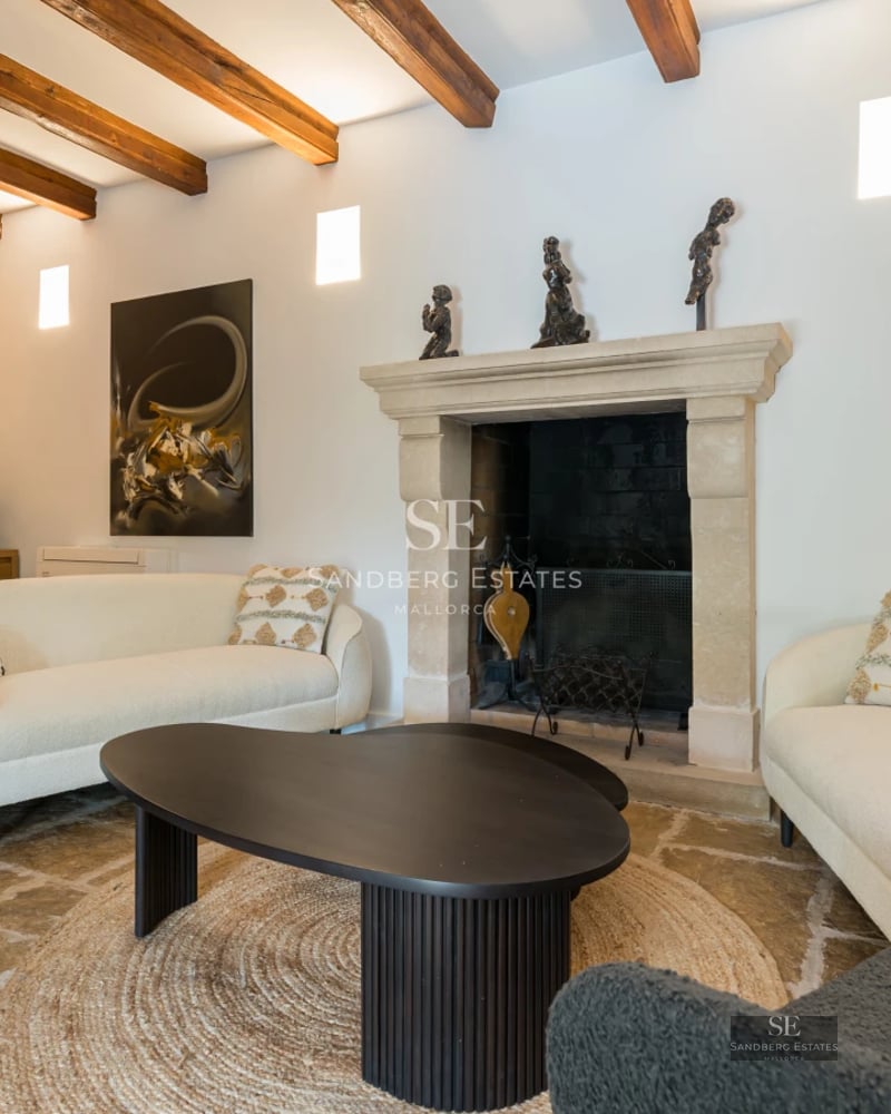 Spacious, bright living room with fireplace, leather sofa, coffee table, and large windows overlooking the garden. Modern and elegant design.