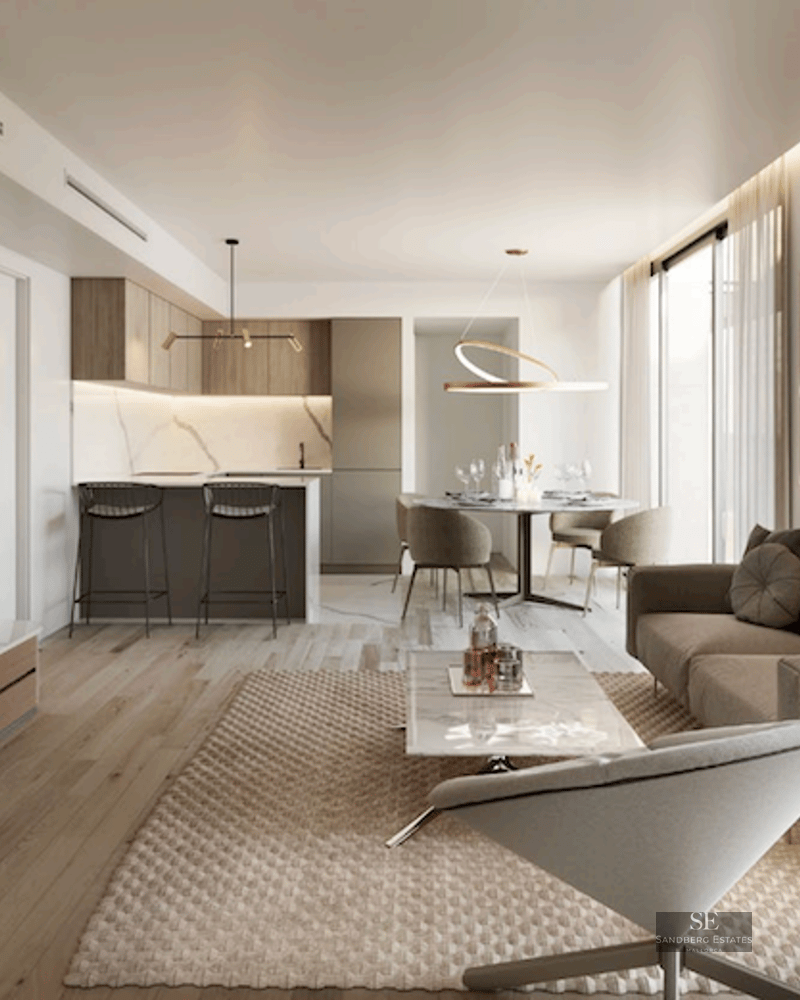 Modern living room featuring a beige sofa, marble coffee table, wood flooring, and an integrated kitchen in the background.