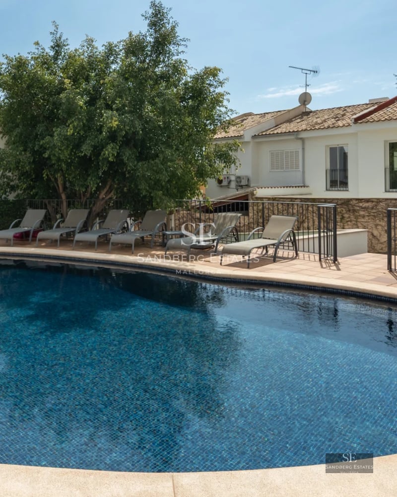 Aerial view of a modern villa featuring a swimming pool, lush garden, and sleek architectural design. Abundant natural lighting.