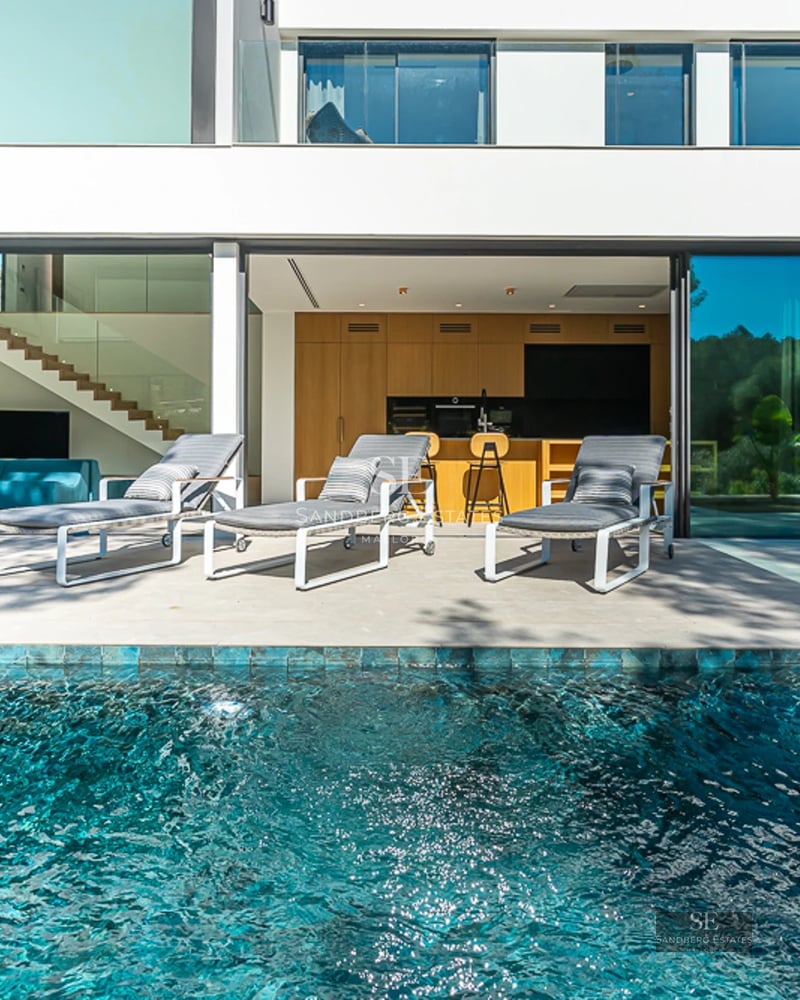 Vue piscine à débordement avec chaises longues. Design moderne, palmiers, ciel bleu. Luxe et confort. Détente au bord de la piscine.