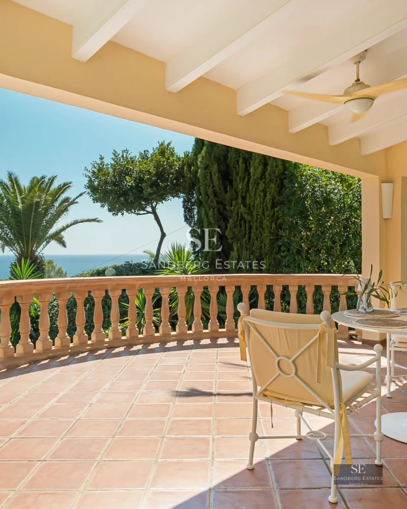 Spacious living room with panoramic windows, light wood floors, beige sofa, and stunning sea view. Modern and bright design.