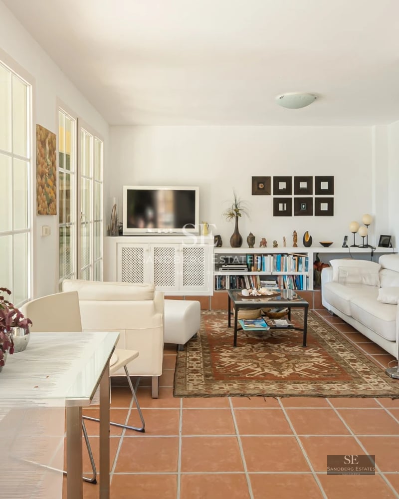 Spacious living room with large windows, light wood floors, gray sofas, and panoramic ocean views. Modern and bright design.