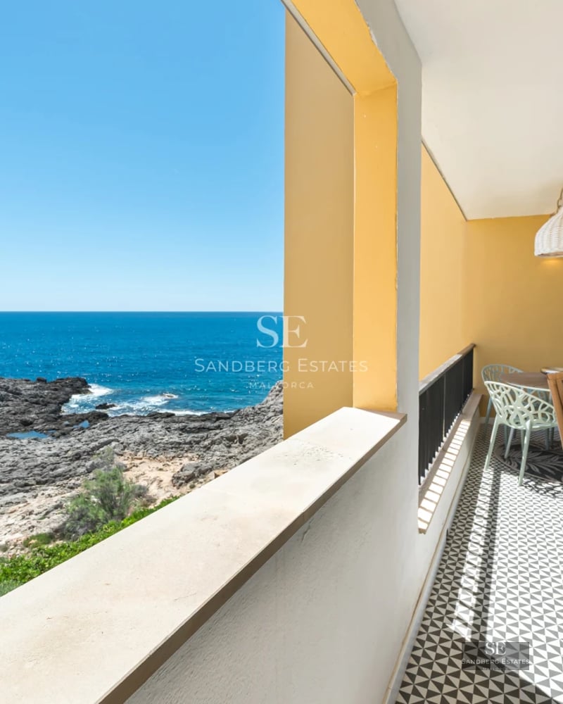 Spacious living room with floor-to-ceiling windows, natural light, wood flooring and sea view. Modern sofa and minimalist decor.