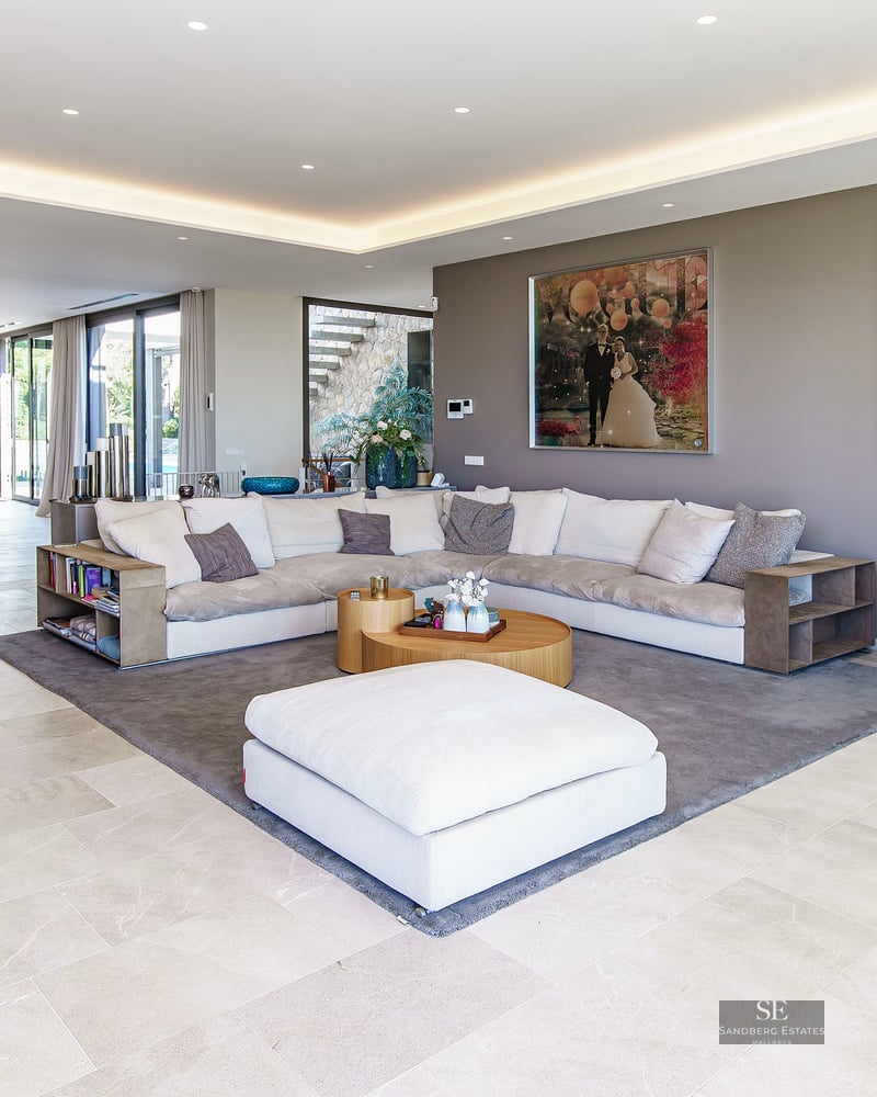 Vaste salon moderne avec canapé en L, télescope et art contemporain sous un éclairage de plafond encastré.