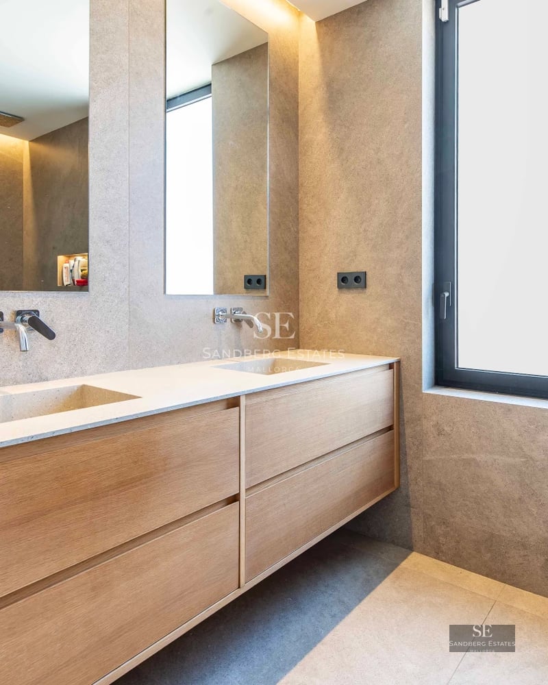 Spacious balcony with sea views. Glass railing, modern furniture, and wooden flooring. Minimalist design and abundant natural light.