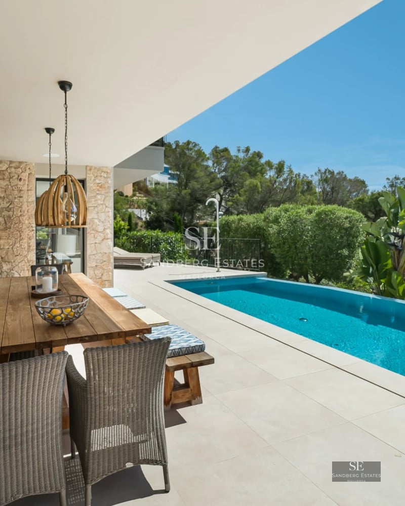 Spacious balcony with panoramic sea views. Modern furniture, glass railing and wooden floor. Elegant and bright design.