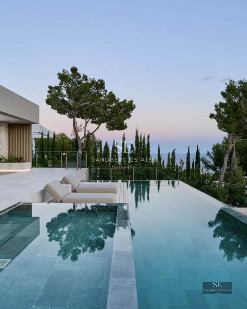 Spacious living room with large windows, modern furniture, light wood floors and access to a balcony with stunning sea views.