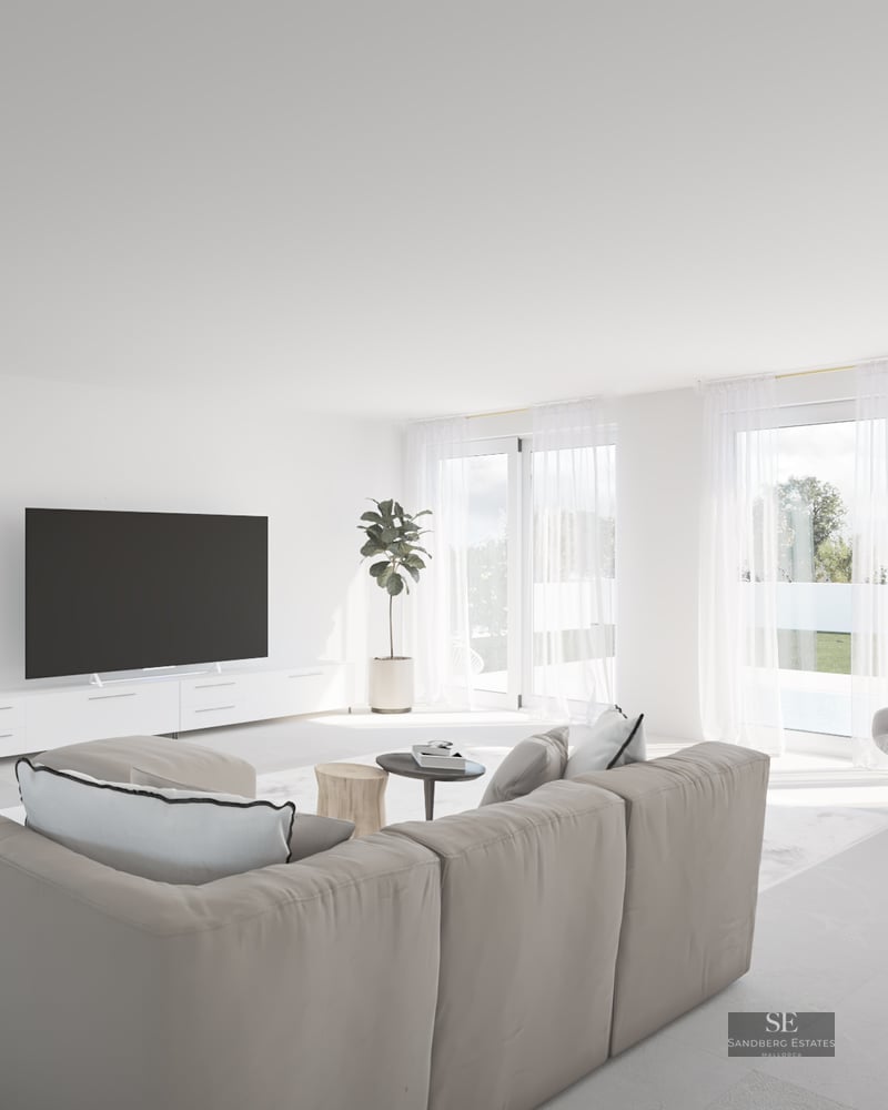 Bright living room with beige sectional sofa, floor-to-ceiling windows, and garden view with pool.