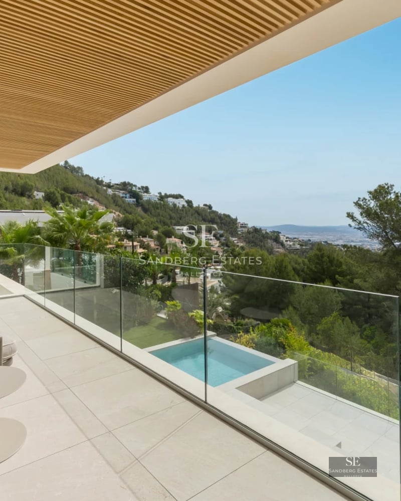 Spacious balcony with panoramic sea views. Modern and elegant furniture, wooden floor, and glass railing.