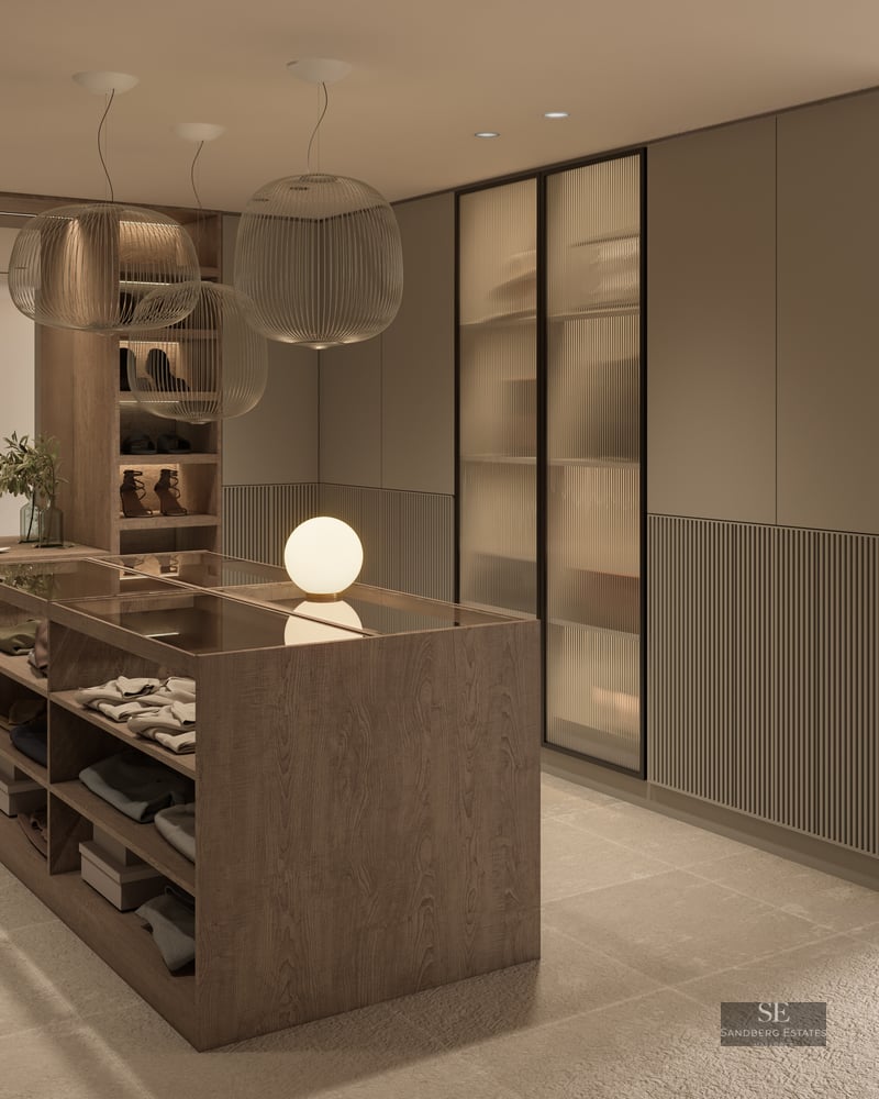 Modern dressing room featuring a central wood island, ribbed glass wardrobes, and elegant sphere pendant lights.