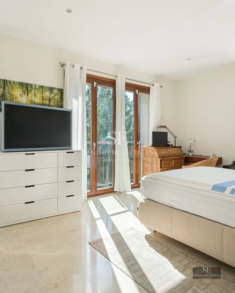 Bright living room with large windows and sea view. Gray sofa, modern coffee table, minimalist decor and wooden floor.