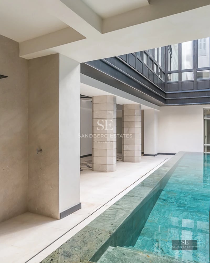 Expansive pool deck surrounded by lush greenery. Modern design with comfortable outdoor furniture. Ambient lighting and relaxing views.