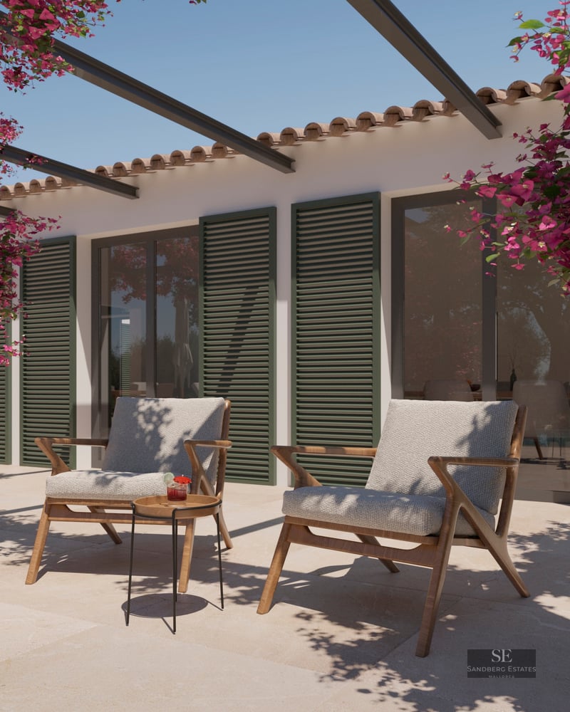 Stone terrace with two wooden armchairs, green shutters, and vibrant pink bougainvillea under a clear sky.