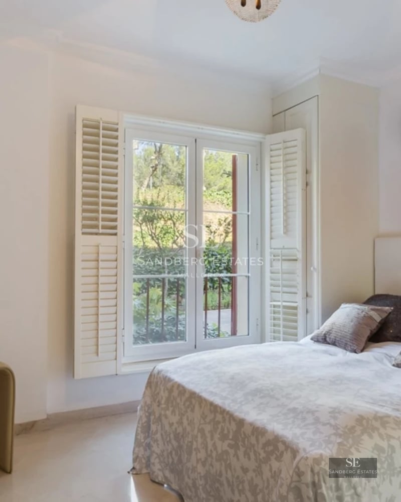 Large infinity pool surrounded by lawn and lush vegetation. Modern architecture with large windows and natural light.