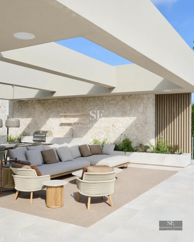 Expansive terrace with infinity pool, ocean views. Modern designer furniture, lush landscaping. Warm ambient lighting.