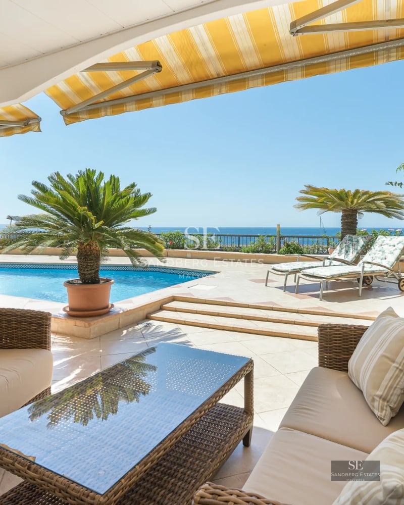 Spacious terrace with infinity pool, modern sun loungers, and sea views. Minimalist design with lush vegetation.