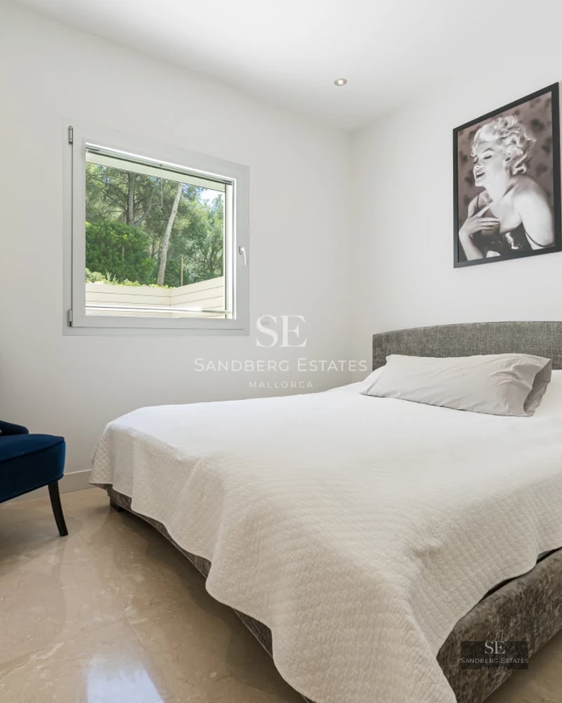 Bright living room with balcony, sea view, and modern furniture. Wooden floors, white walls, and minimalist decor.