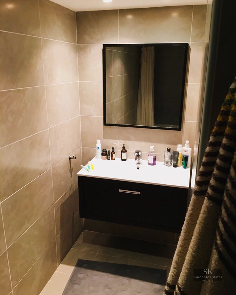 Grand balcon avec vue sur la mer, garde-corps en verre, plancher en bois et mobilier d'extérieur moderne. Design minimaliste et lumière naturelle abondante.