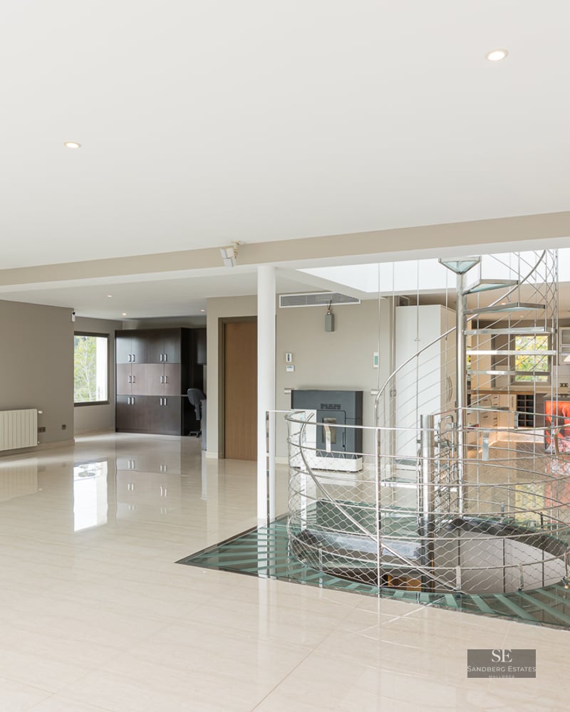 Large modern living area featuring polished marble floors and a central metal and glass spiral staircase.