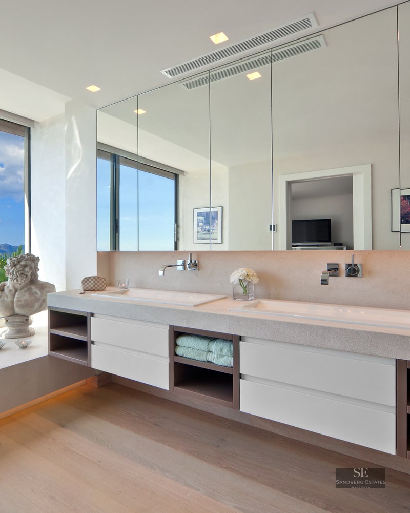 Modern master bathroom featuring a double vanity and a floor-to-ceiling window overlooking the sea.