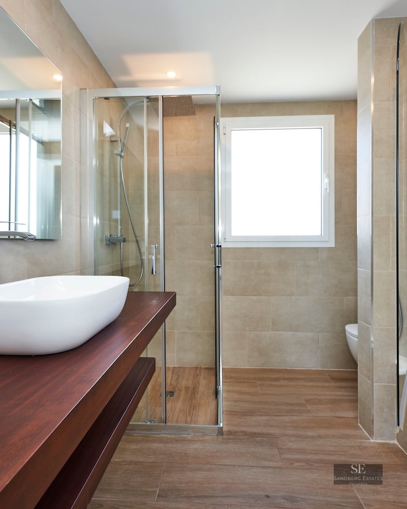 Modern bathroom featuring a white vessel sink on a wood vanity, a glass shower, and a built-in bathtub.