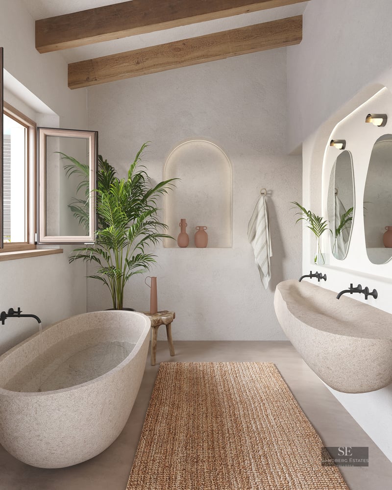 Carved stone bathtub and long stone sink in a bathroom with exposed wooden beams, plaster walls, and an arched niche.